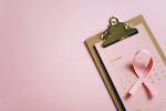 An overhead shot of an October calendar with a pink ribbon on a clipboard, symbolizing breast cancer awareness.
