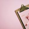 An overhead shot of an October calendar with a pink ribbon on a clipboard, symbolizing breast cancer awareness.