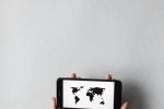Hands holding a smartphone displaying a world map on a white background, emphasizing global connectivity.