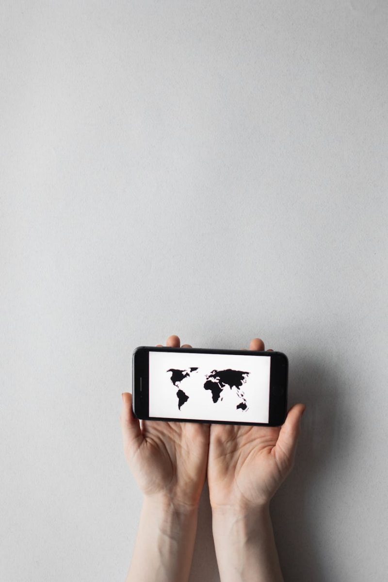 Hands holding a smartphone displaying a world map on a white background, emphasizing global connectivity.