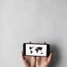 Hands holding a smartphone displaying a world map on a white background, emphasizing global connectivity.