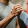 Close-up of a handshake between two individuals in a gym, symbolizing support and teamwork.