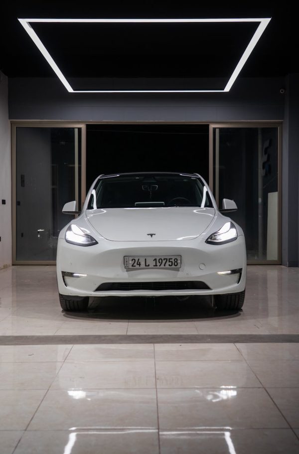 White electric car showcased in a minimalist indoor showroom with a contemporary design.