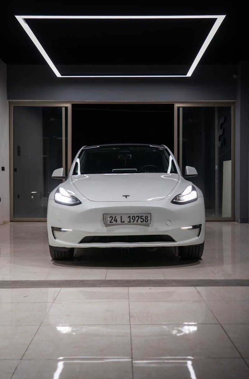 White electric car showcased in a minimalist indoor showroom with a contemporary design.