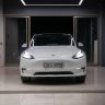 White electric car showcased in a minimalist indoor showroom with a contemporary design.
