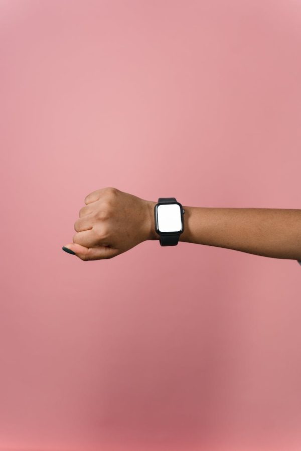 Hand displaying a smartwatch against a pink background, perfect for design mockups.