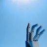 Robotic hand with articulated fingers reaching towards the sky on a blue background.