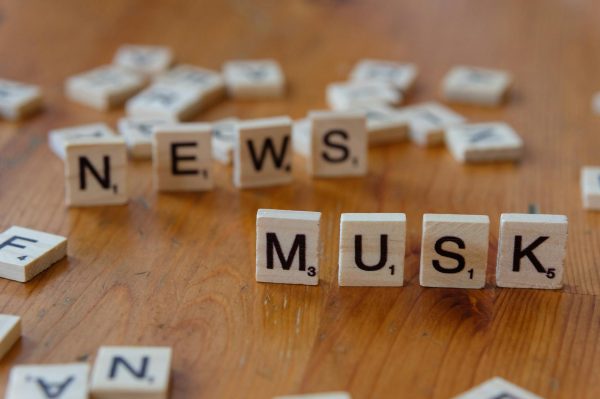 Close-up of wooden letter tiles on a table spelling 'News Musk', concept of media coverage.