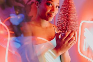 Woman holding a pink Christmas tree with vibrant neon lights.