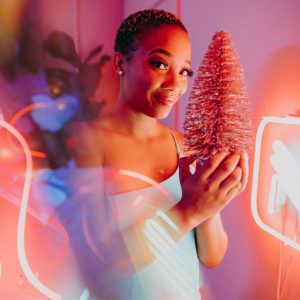 Woman holding a pink Christmas tree with vibrant neon lights.